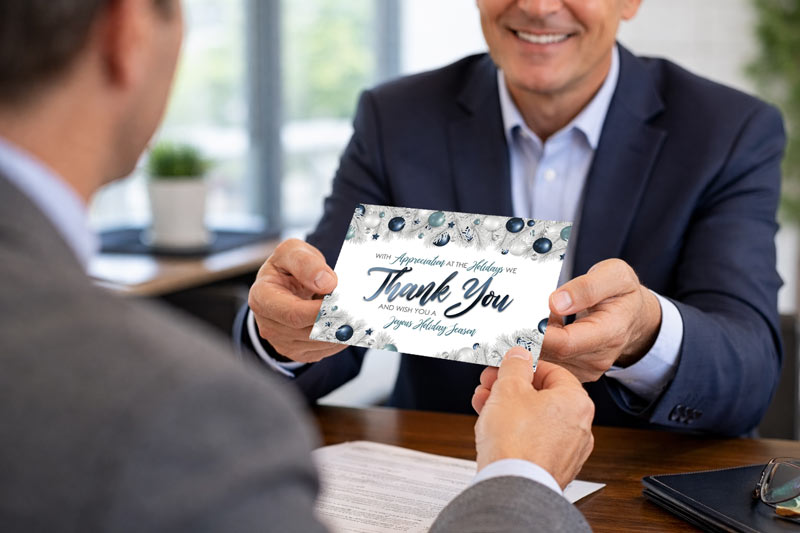 Business professional giving a greeting card to a client as part of relationship marketing.