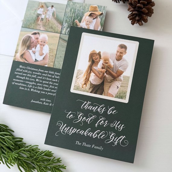 Dark green folded Christmas photo card featuring a centered family photo and white script greeting; back shows a multi-photo collage and holiday message.