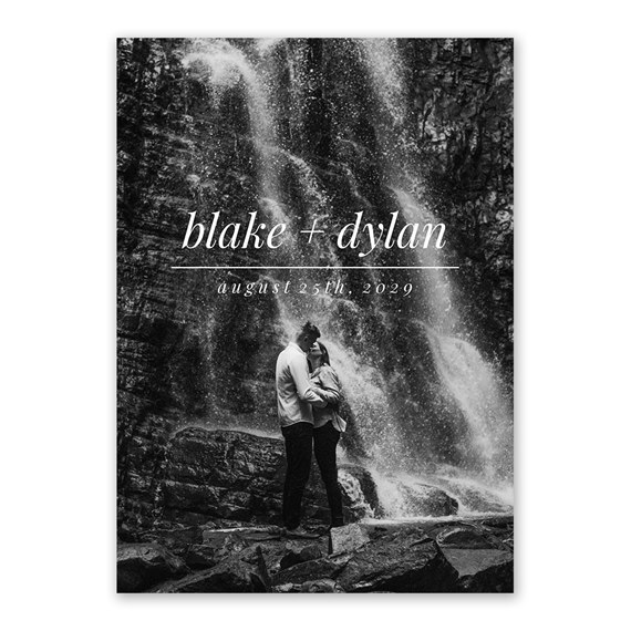 black and white wedding invitation featuring a couple embracing at a waterfall with script text and a horizontal line