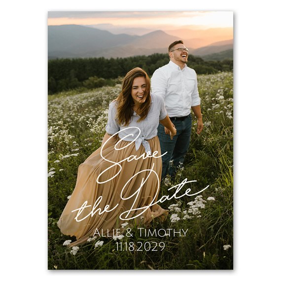 Couple in a wildflower meadow save-the-date magnet with white script text and date overlay