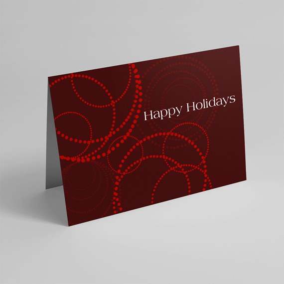 Folded burgundy holiday greeting card with red dotted circles and white "Happy Holidays" text