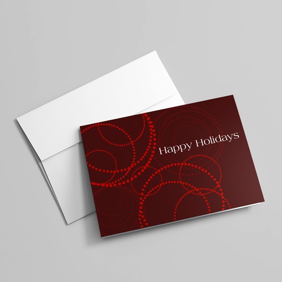 Folded burgundy holiday card with red dotted circles and "Happy Holidays" text beside a white envelope