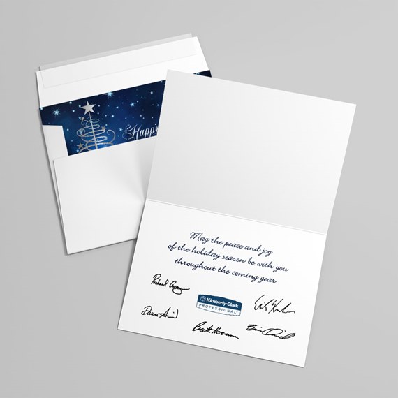 Folded white holiday greeting card with blue printed message and signatures, white envelope with dark blue starry liner