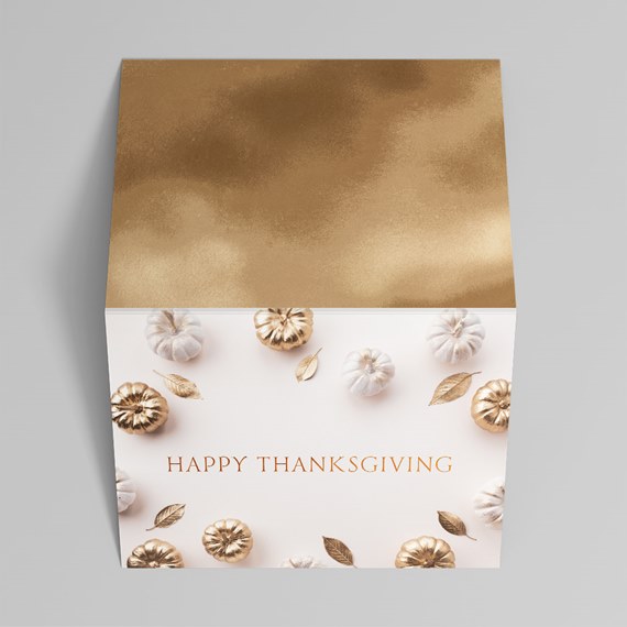 square Thanksgiving gift box with gold lid and white base decorated with pumpkins and gold leaves