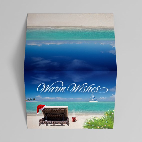 beach scene with lounge chair, Santa hat, and warm wishes text