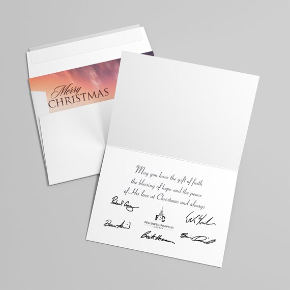 Open Christmas greeting card showing printed message, signatures and a church logo, with envelope and 'Merry Christmas' liner.