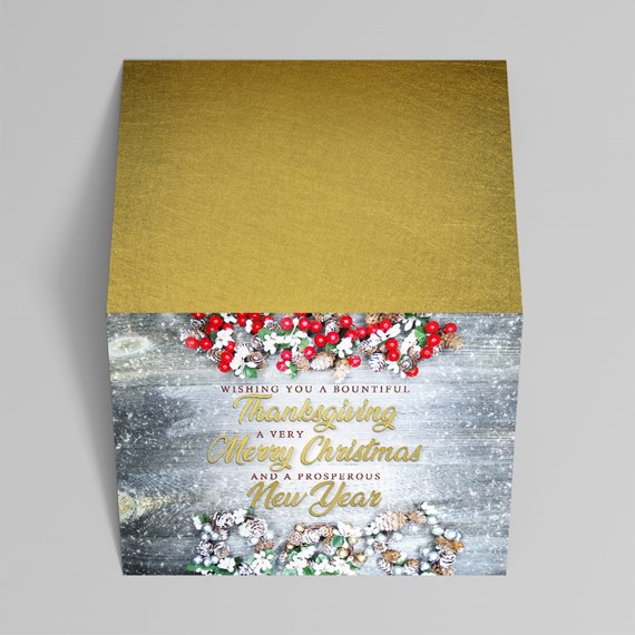 Folded holiday greeting card with gold cover, rustic gray wood panel, red berry and pinecone garlands and multi-holiday greeting text