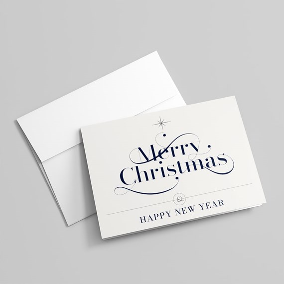 Folded white Christmas greeting card with navy calligraphy text and matching white envelope