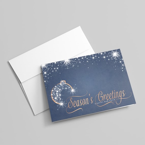 navy-blue holiday greeting card with white sparkles, ornament illustration and gold 'Season's Greetings' calligraphy beside a white envelope