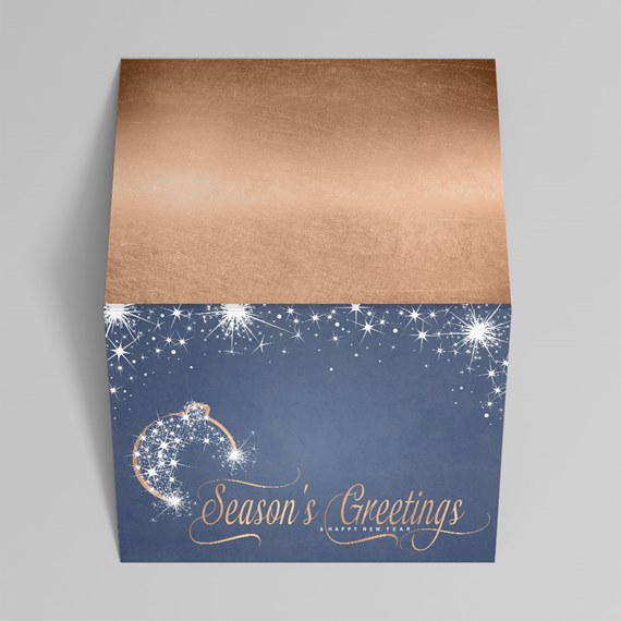 Folded holiday greeting card with rose-gold top, navy front, white starburst accents and "Season's Greetings" text
