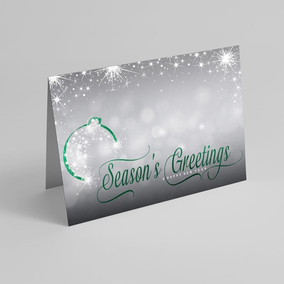 Folded holiday greeting card with silver-gray bokeh background, white star sparkles and green script reading Season's Greetings