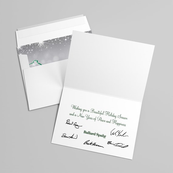 open white folded holiday greeting card with green printed message and signatures, with envelope and snowflake liner