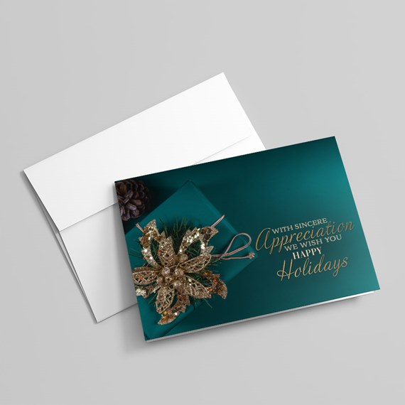 Teal holiday greeting card with gold glitter poinsettia, pine cone, ribbon accents and white envelope