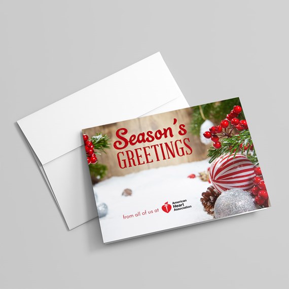Folded holiday greeting card reading "Season's Greetings" with red striped ornament, silver bauble, pinecones, evergreen sprigs and red berries, shown with white envelope.
