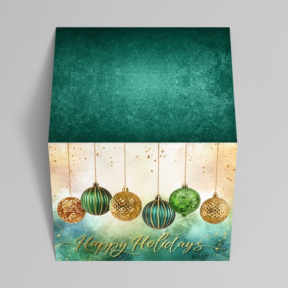 Folded holiday greeting card with green and gold hanging ornaments, gold "Happy Holidays" text and textured teal interior