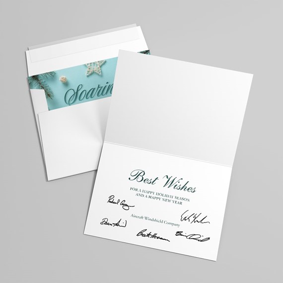 white folded holiday greeting card with teal interior panel, pine sprig, decorative star, "Best Wishes" text and printed signatures next to an envelope