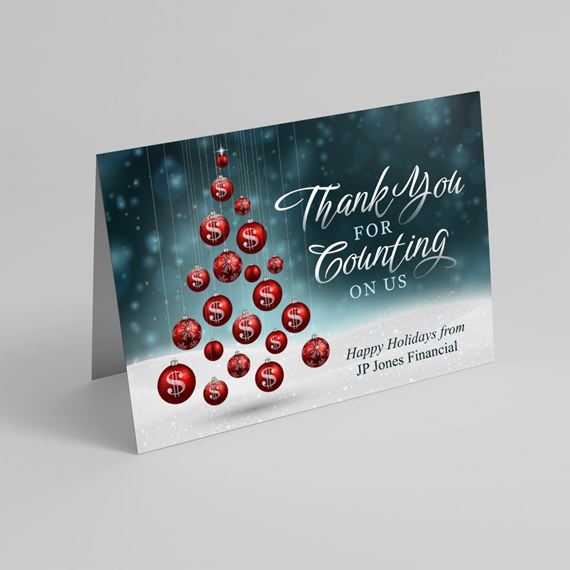 folded holiday card with red dollar-sign ornaments forming a tree on a teal background