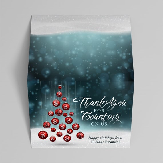 folded holiday card with red dollar-sign ornaments arranged as a tree against a teal bokeh background and snow