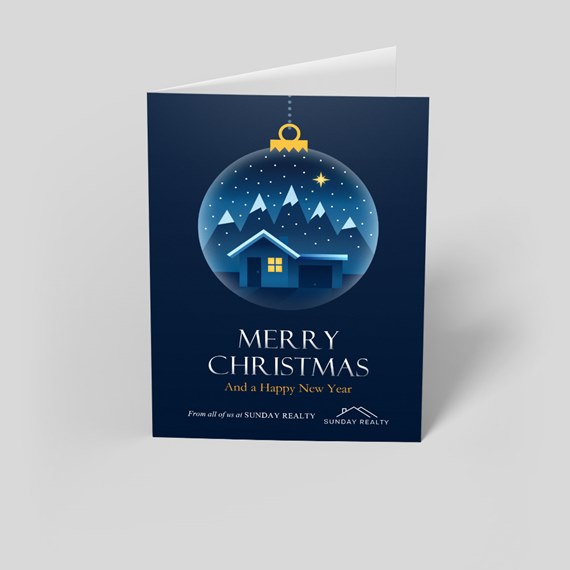 Navy folded Christmas greeting card with snow-globe ornament showing a house, mountains, star and 'Merry Christmas' text.