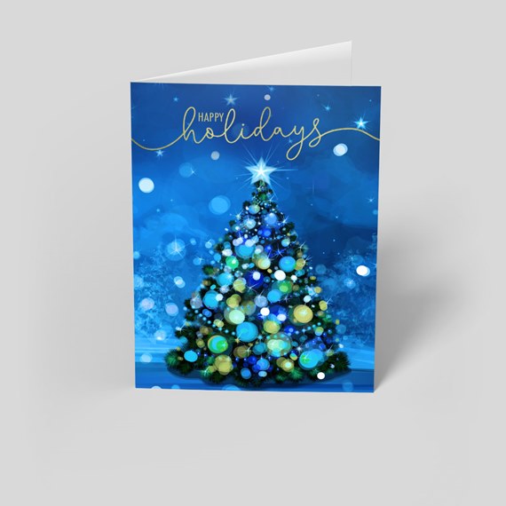 Folded holiday greeting card with decorated Christmas tree and gold Happy Holidays script on blue background