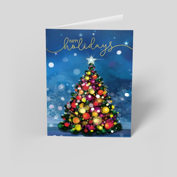 Folded holiday card with a decorated Christmas tree, colorful ornaments and 'Happy Holidays' text on a blue background.