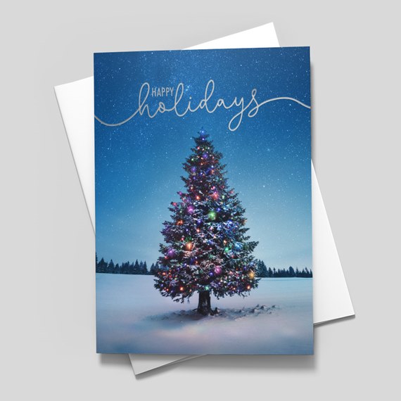 Holiday greeting card with decorated Christmas tree in snow and 'Happy holidays' script