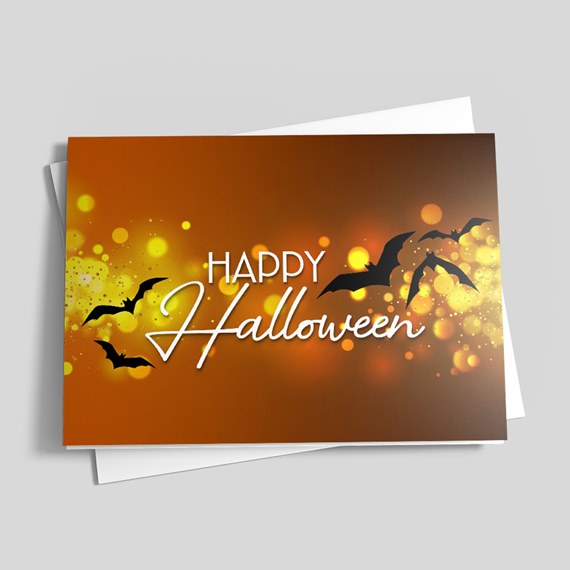 Folded Halloween greeting card reading 'Happy Halloween' with orange and yellow bokeh background and black bats