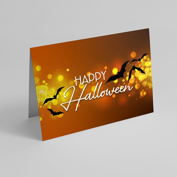 Folded Halloween greeting card with 'Happy Halloween' white script, black bats and yellow bokeh on an orange background.