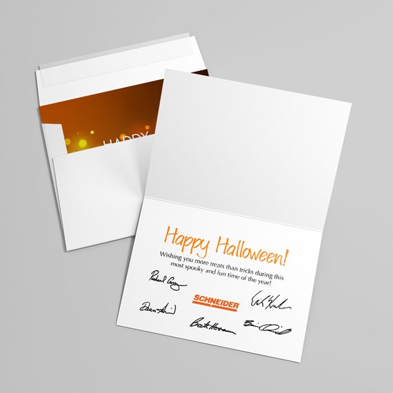 white folded Halloween greeting card with orange script, printed message and signatures, shown with envelope and orange bokeh interior