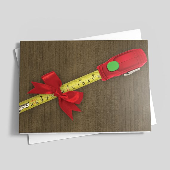 Folded greeting card with a yellow measuring tape tied with a red ribbon on a wood background, envelope underneath