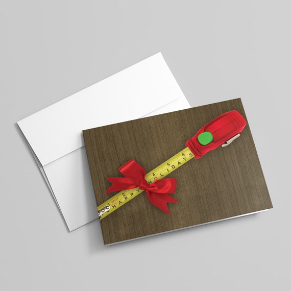 wood-texture greeting card with measuring tape, red bow and red tape-measure tool with white envelope