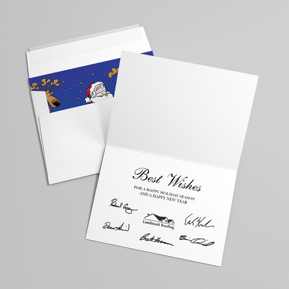 Folded white holiday greeting card reading 'Best Wishes' with signatures and an open envelope showing a blue liner with cartoon Santa and reindeer
