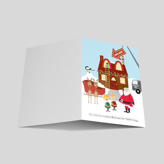 Folded Christmas greeting card with illustrated snowy scene showing a decorated house, Santa, elves, reindeer and a snowman