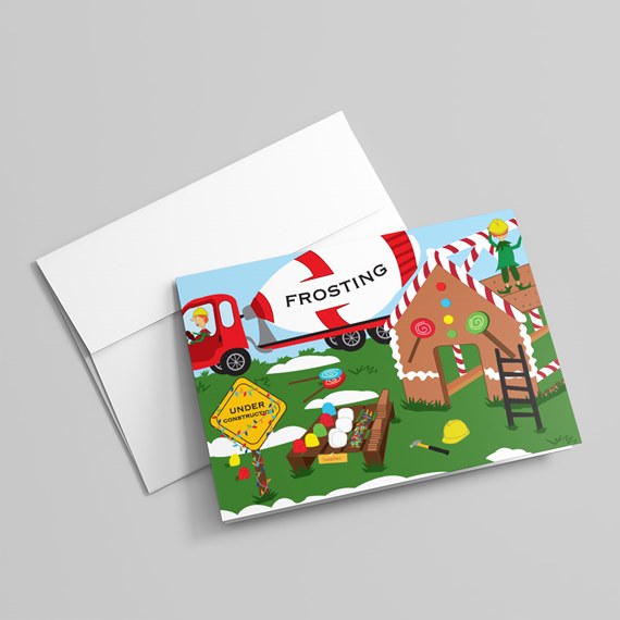 Folded holiday card depicting a gingerbread house under construction with a frosting truck, candy and construction workers, shown with envelope.