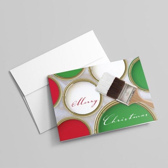 Folded Christmas greeting card with red, green, and white paint cans, paintbrush and 'Merry Christmas' text, with white envelope