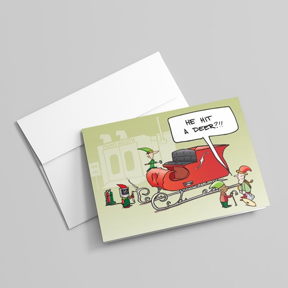 Folded greeting card showing elves repairing a dented red sleigh with a speech bubble that reads He hit a deer?!!, includes white envelope