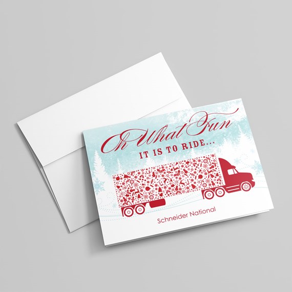 Folded holiday greeting card with red semi-truck and patterned trailer on a light blue snowy background, shown with a white envelope