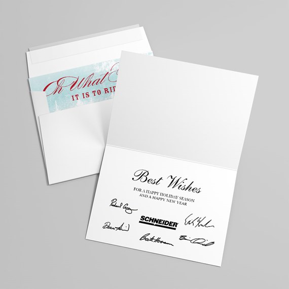 White folded holiday greeting card open to show 'Best Wishes' printed message and signatures, with matching envelope and light blue patterned liner
