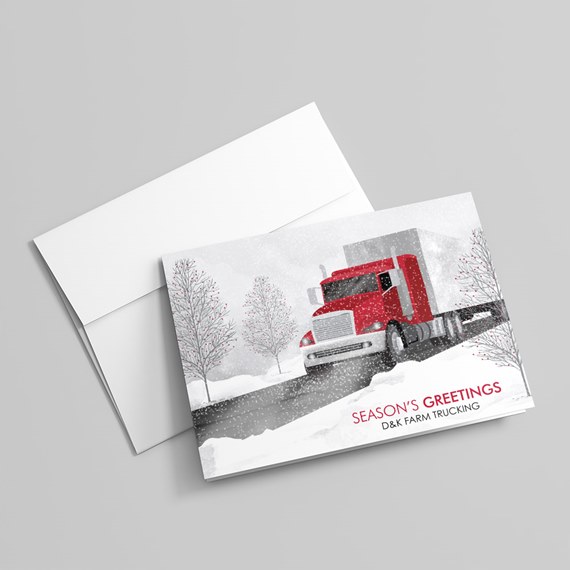 Holiday greeting card with a red semi truck on a snowy road and bare trees, paired with a white envelope