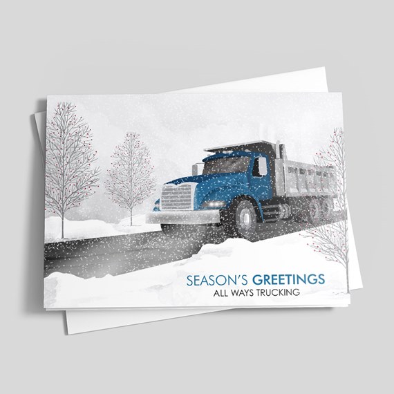 Holiday greeting card showing a blue dump truck in a snowy winter scene with bare trees and the text "Season's Greetings"