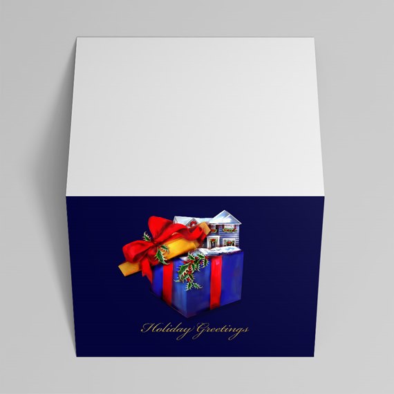 Folded holiday greeting card with navy front showing a blue gift box topped by a small snowy house, red bow and holly, and gold "Holiday Greetings" script; white top.