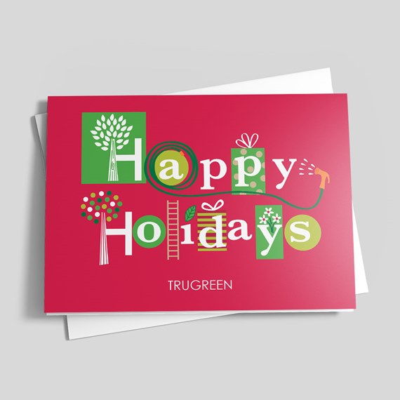 Folded red holiday greeting card with white and green 'Happy Holidays' typography and small gift and tree illustrations, with envelope