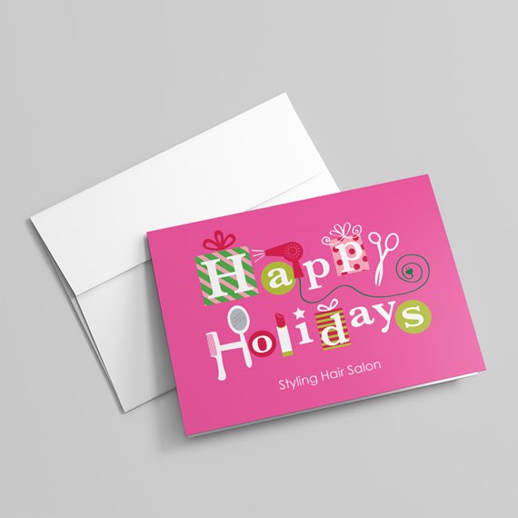 Pink folded greeting card reading 'Happy Holidays' with hair styling icons and a white envelope