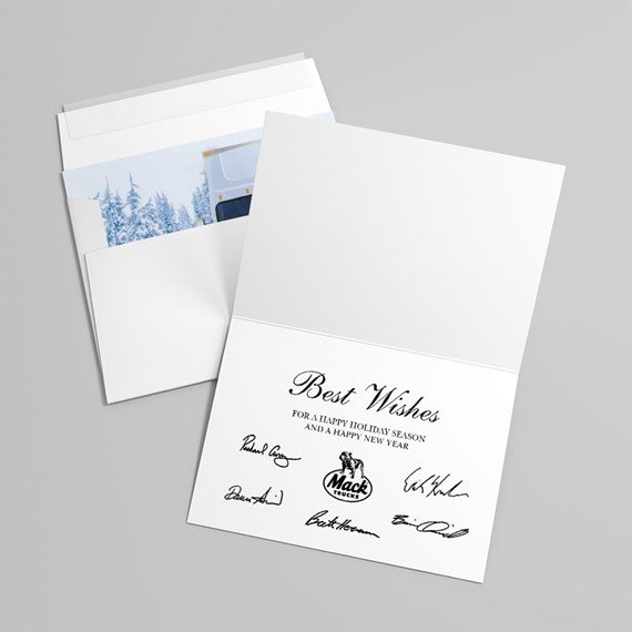 white folded holiday greeting card open to show 'Best Wishes' message, printed signatures and small truck emblem, with envelope and snowy blue insert
