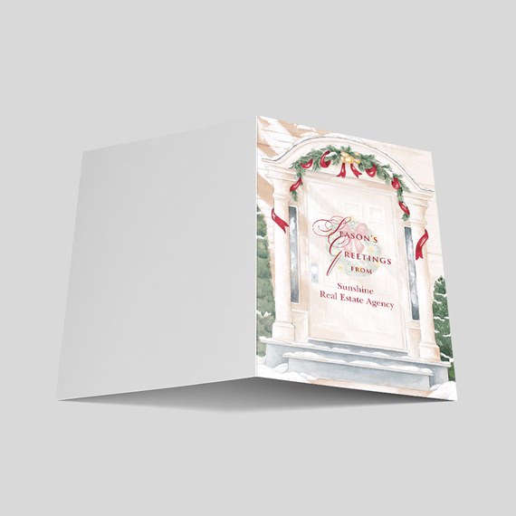 Folded holiday greeting card with illustrated front porch, evergreen garland, red ribbons and snowy steps